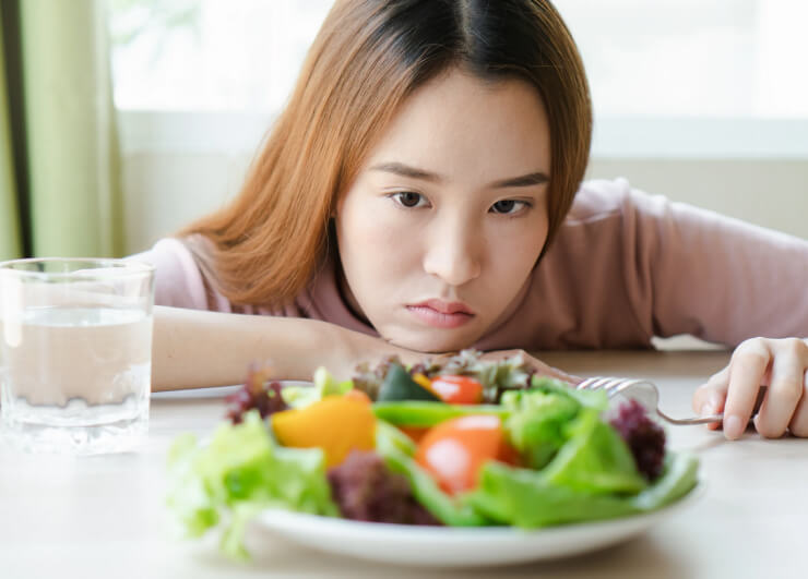 девушка смотрит на тарелку с салатом